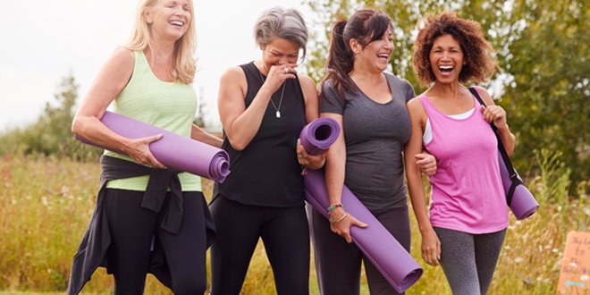 Group Of Mature Female Friends On Outdoor Yoga Retreat Walking Along Path Through Campsite