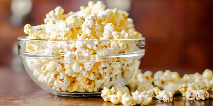 Closeup Popcorn in a glass cup on a wooden table and blurry background. popcorn