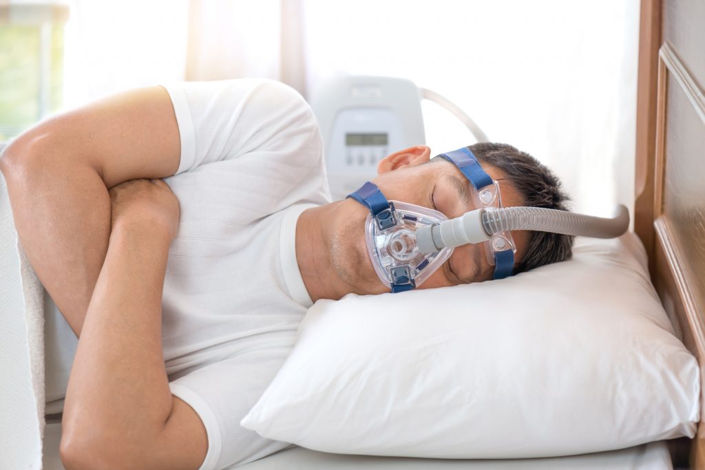 Man sleeping in bed wearing CPAP mask ,sleep apnea therapy sleep disturbances