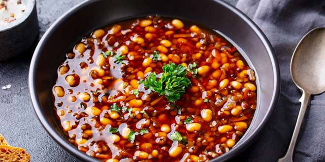 Bean soup in a black bowl. Dark background. Close up. kidney beans