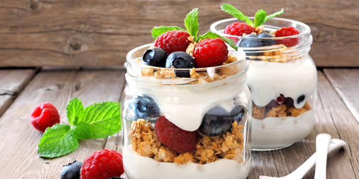 Blueberry, raspberry parfaits in mason jars, still life against wood yogurt