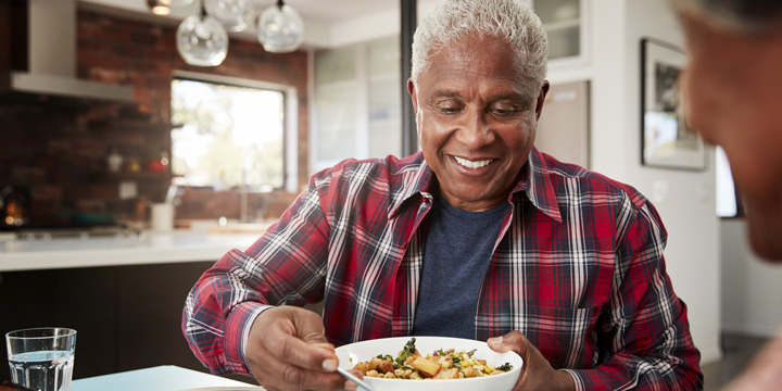 Senior Couple Enjoying Meal Around Table At Home