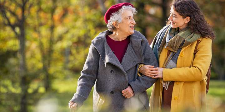 Senior woman walking with granddaughter in park during autumn