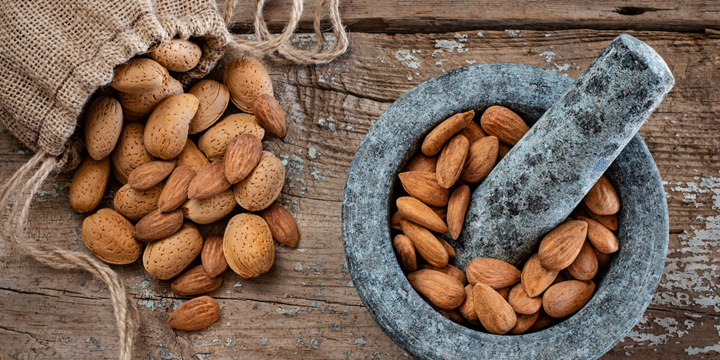 Many almonds in the stone mortar and sack bag.
