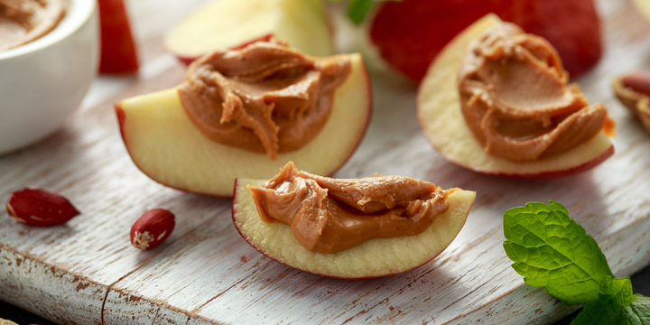 Peanut butter and apple to snack. on white wooden board
