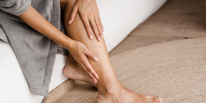Deep vein thrombosis and varicose of african woman. Girl touching her legs and looking at veins. Sclerotherapy procedure at visiting vascular surgeon doctor.