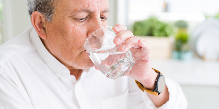 Handsome senior man drinking a fresh glass of water at home