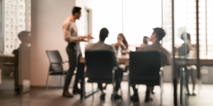 Colleagues having meeting in boardroom, businessman giving speech, blurred photo
