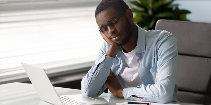 African employee falls asleep seated on chair at workplace