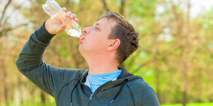 Horizontal portrait of a man drinking water from small bottle