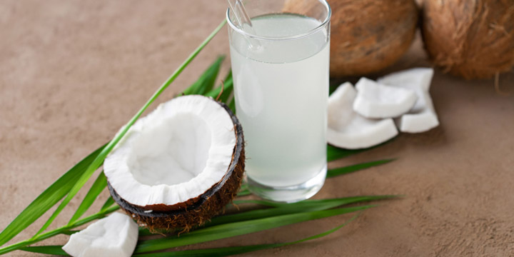 image of glass of coconut water, coconuts and palm leaf