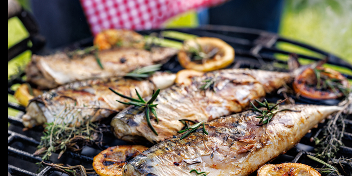 Grilled mackerel fish with the addition of herbs and lemon slices on the grill