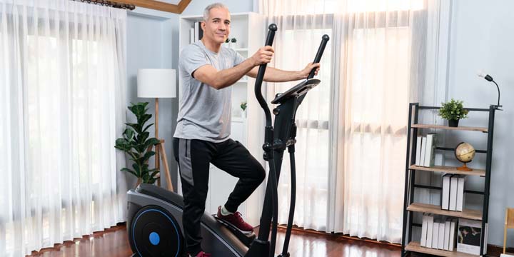 Active senior man running on elliptical running machine. Clout