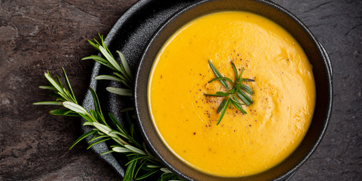 Pumpkin soup with linen napkin on dark background.