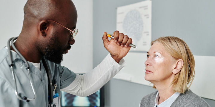 Young confident opthalmologist examining retina of mature female patient