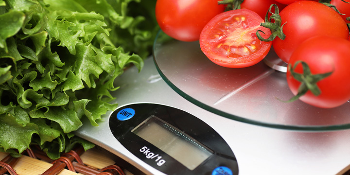 Fresh tomatoes on kitchen scales weighing