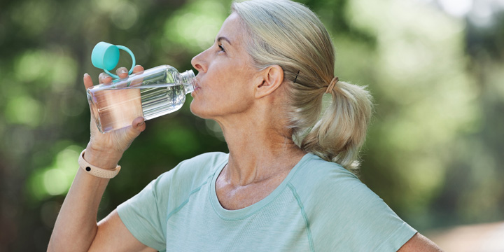 Shot of a mature woman drinking water while exercising outdoors drink water