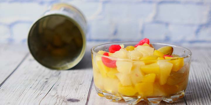 Open can of fruit cocktail on table , canned fruit