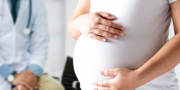 Pregnant Woman and Gynecologist Doctor at Hospital Happy pregnant woman visit gynecologist doctor at hospital or medical clinic for pregnancy consultant. Doctor examine pregnant belly for baby and mother healthcare check up. Gynecology concept.