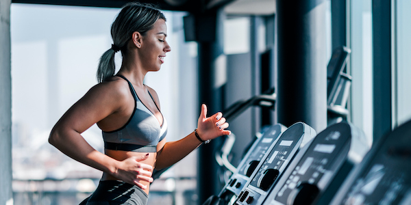 Side view of beautiful muscular woman running on treadmill. Side view of beautiful muscular woman running on treadmill.