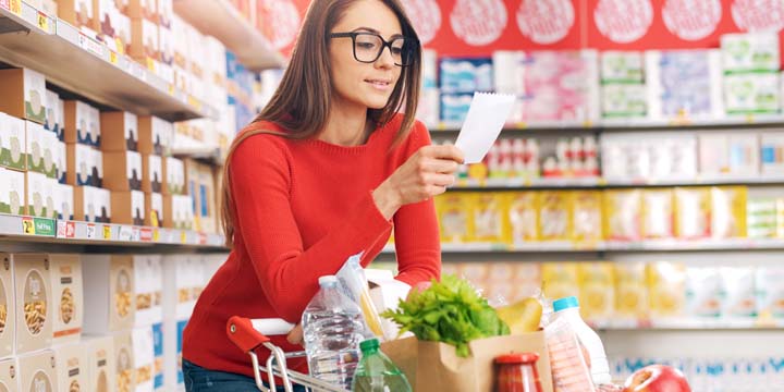Beautiful woman checking her grocery list at the supermarket grocery list